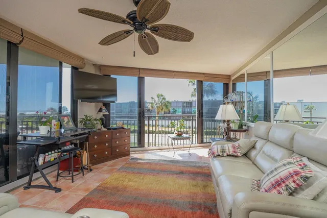 a living room with furniture a flat screen tv and a floor to ceiling window