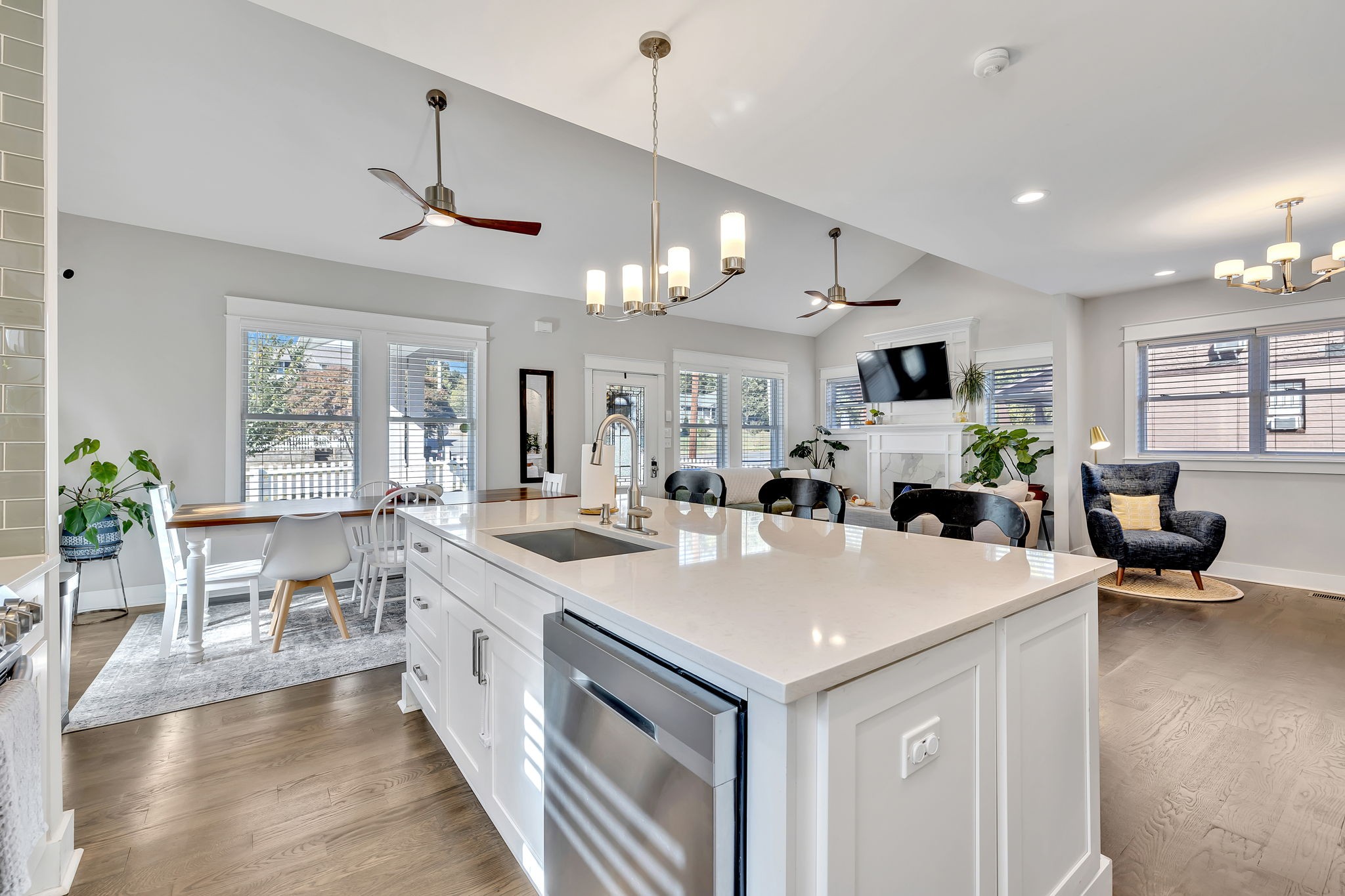 a view of living room kitchen with stainless steel appliances kitchen island a table chairs and a chandelier