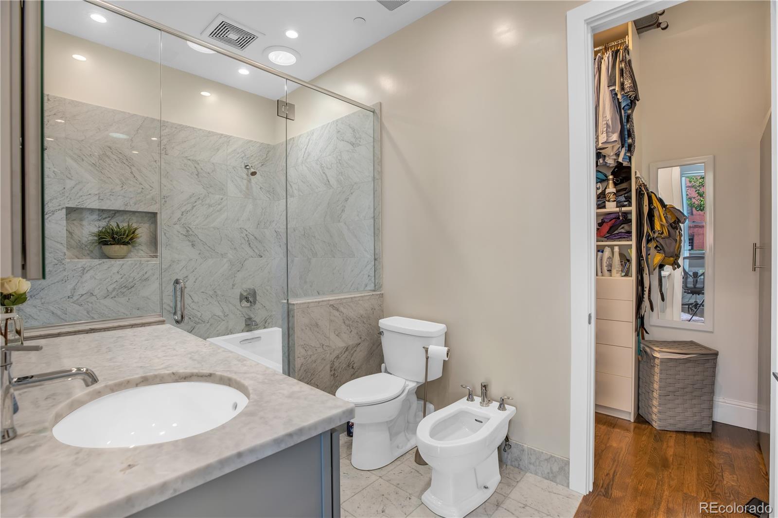 1501 Wazee Street, Unit 4B Denver, CO 80202 - Photo 18 of 40 a bathroom with a granite countertop sink toilet a mirror and shower