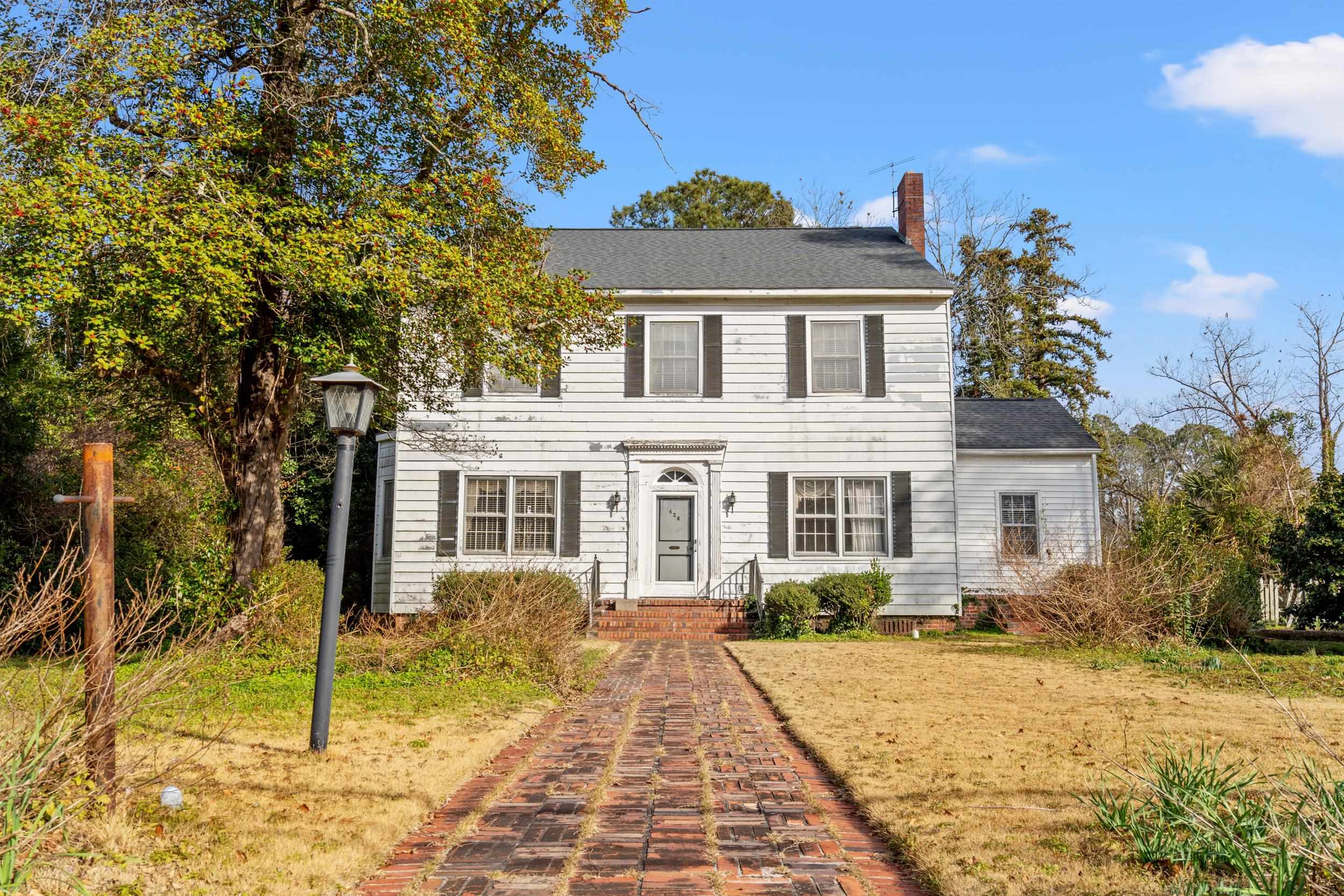 Colonial house featuring a chimney and a shingled roof