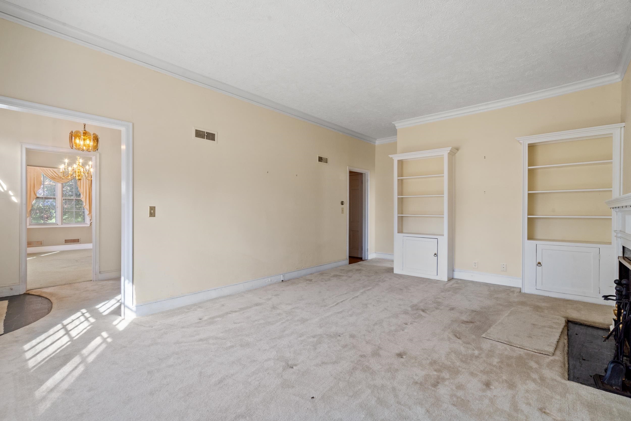 426 North Park Street Mullins, SC 29574 - Photo 11 of 39 Unfurnished living room featuring carpet, ornamental molding, a fireplace, built in features, and a chandelier