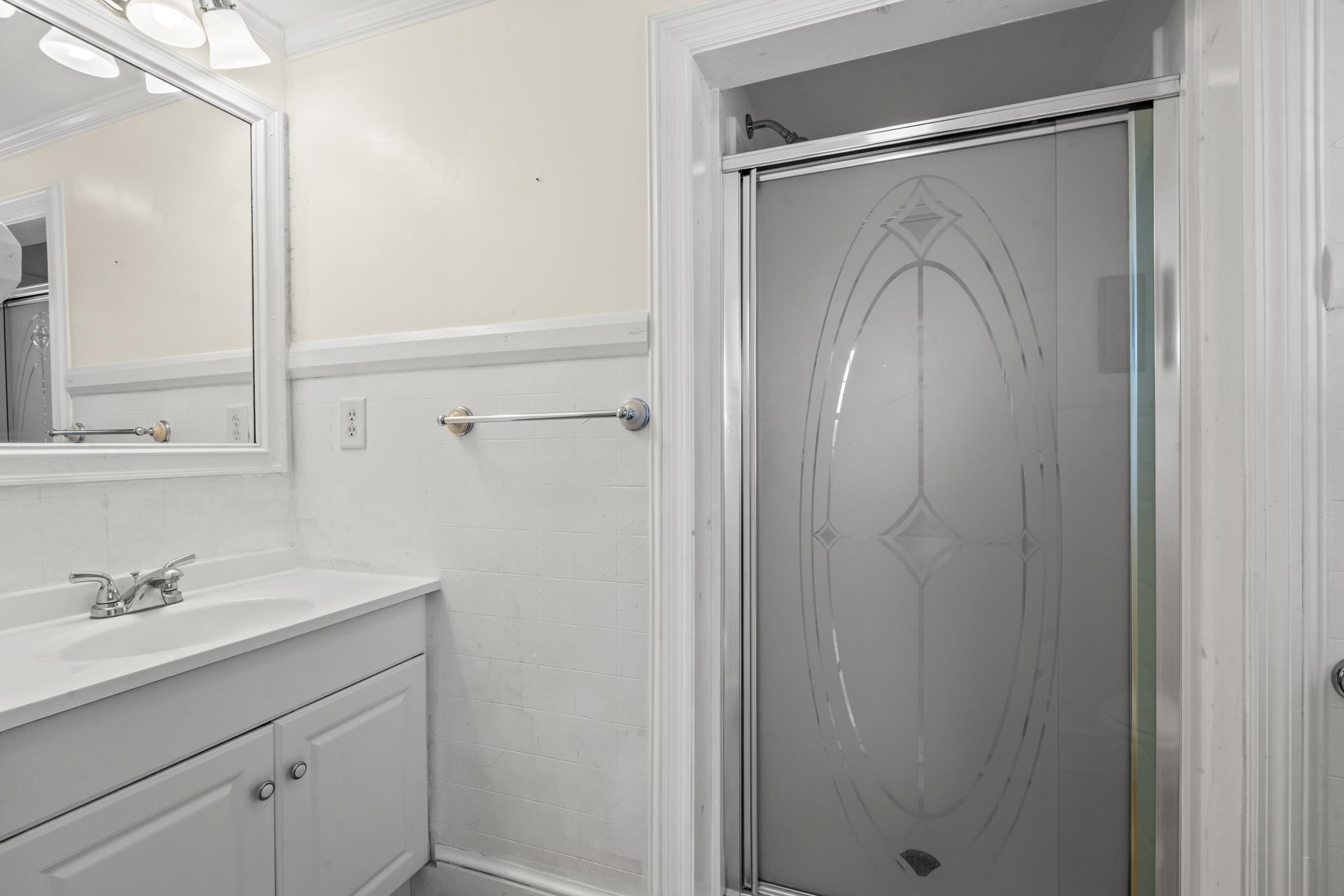 426 North Park Street Mullins, SC 29574 - Photo 16 of 39 Bathroom featuring a stall shower, vanity, crown molding, and a wainscoted wall