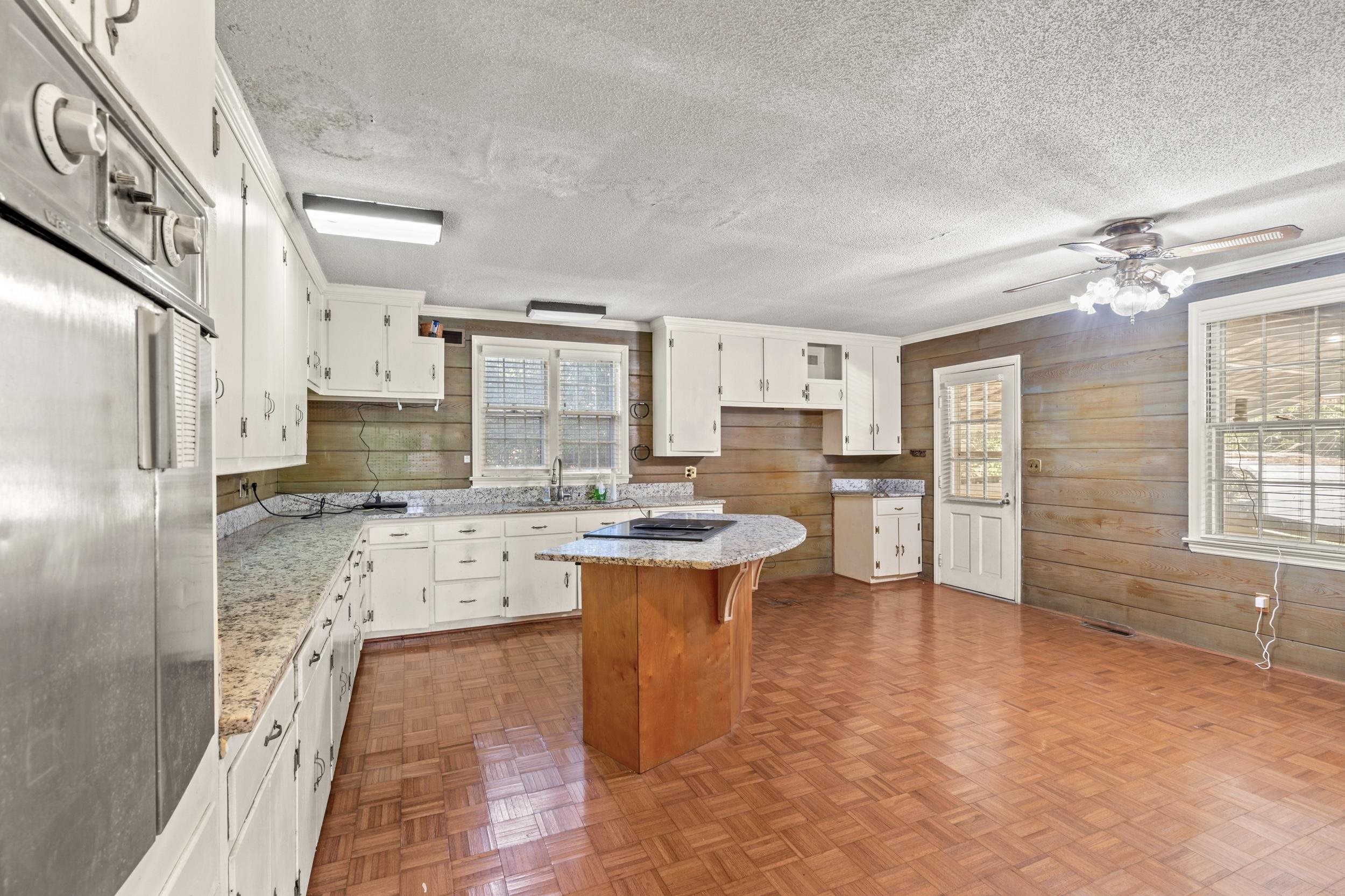 426 North Park Street Mullins, SC 29574 - Photo 2 of 39 Kitchen with parquet flooring, white cabinetry, a textured ceiling, a ceiling fan, and light stone counters
