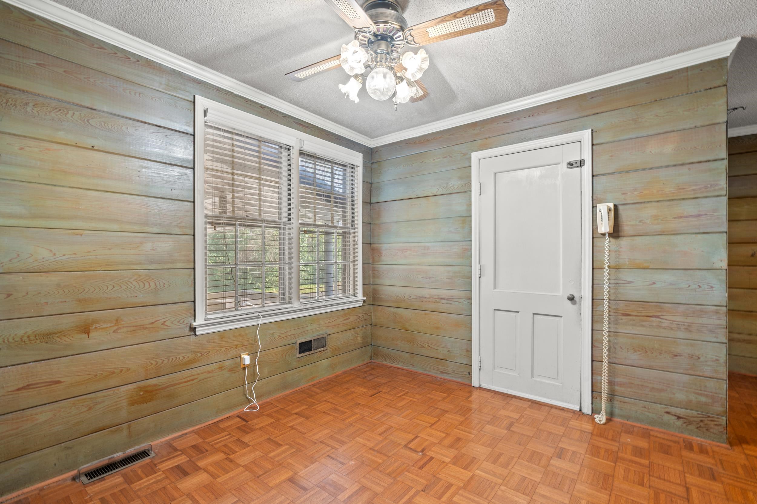 426 North Park Street Mullins, SC 29574 - Photo 4 of 39 Empty room with wood walls, parquet flooring, a textured ceiling, and crown molding