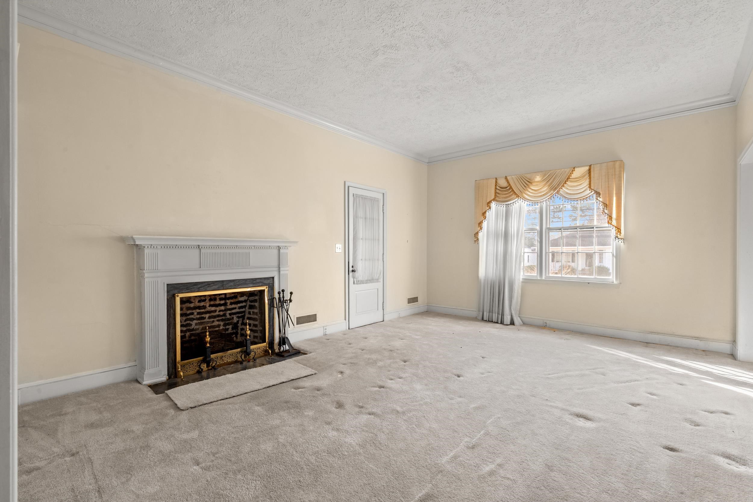 426 North Park Street Mullins, SC 29574 - Photo 9 of 39 Unfurnished living room featuring a premium fireplace, carpet floors, a textured ceiling, and ornamental molding