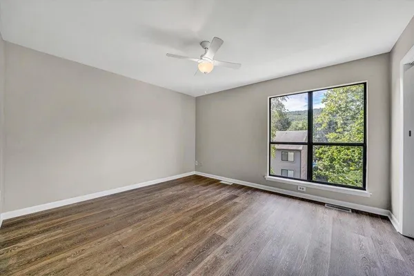 a view of an empty room with wooden floor and a window