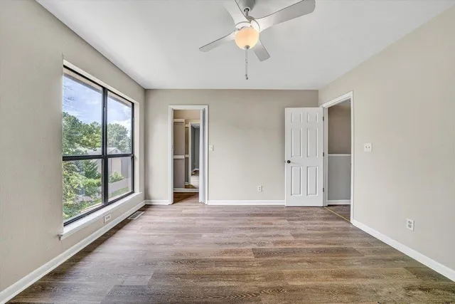 a view of an empty room with a window and a dresser