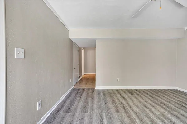 a view of an empty room with wooden floor and a bathroom
