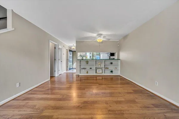 an empty room with wooden floor fireplace and windows