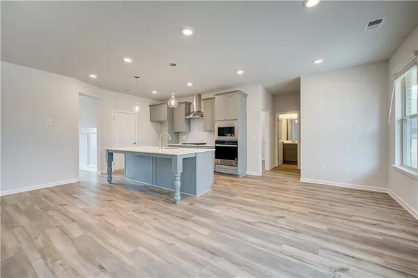a view of kitchen with kitchen island wooden floor center island and stainless steel appliances