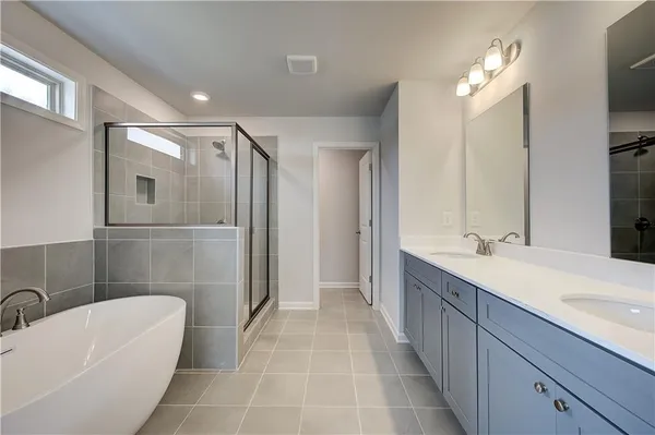 a spacious bathroom with a double vanity sink a large mirror and a bathtub