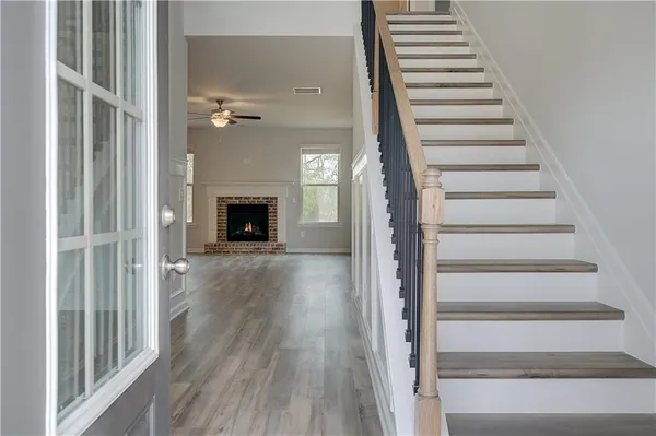 a view of a hallway with wooden floor fireplace and windows