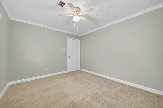 an empty room with a chandelier fan and windows