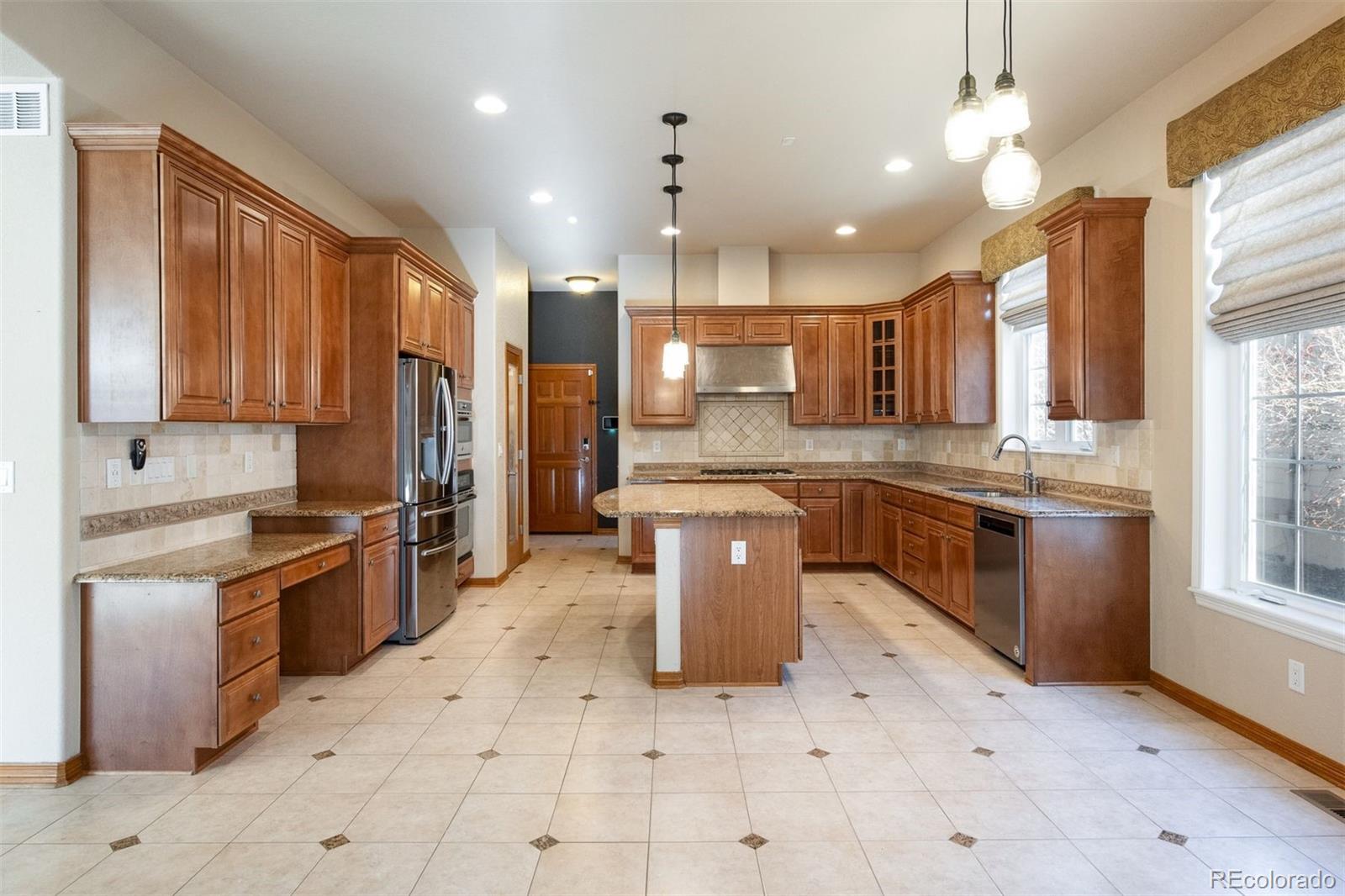 4940 West 107th Loop Westminster, CO 80031 - Photo 5 of 44 a large kitchen with stainless steel appliances kitchen island granite countertop a stove a sink dishwasher and a refrigerator