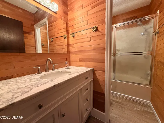 an empty room with wooden floor ceiling fan and windows