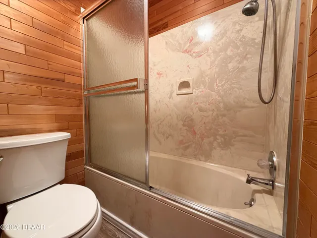 an empty room with wooden floor and a ceiling fan