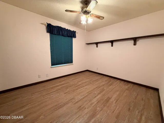 an empty room with wooden floor and ceiling fan