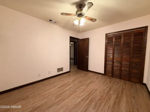 an empty room with wooden floor and ceiling fan