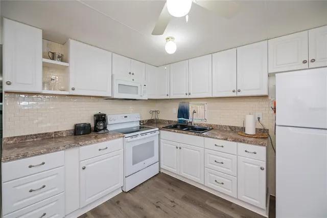a kitchen with granite countertop white cabinets white stainless steel appliances and sink