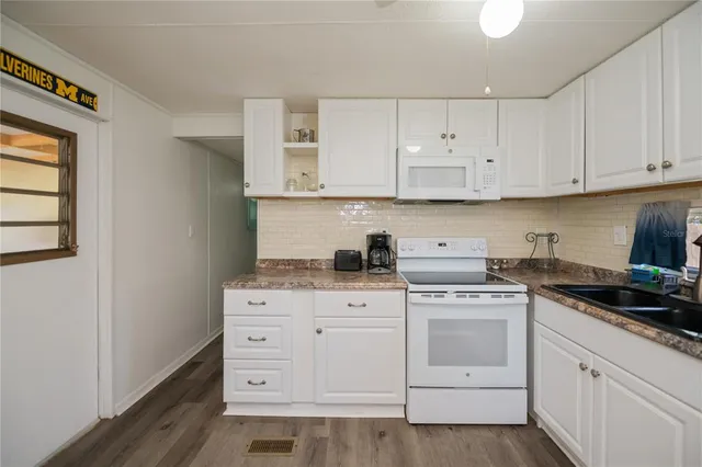 a kitchen with cabinets appliances and a wooden floor