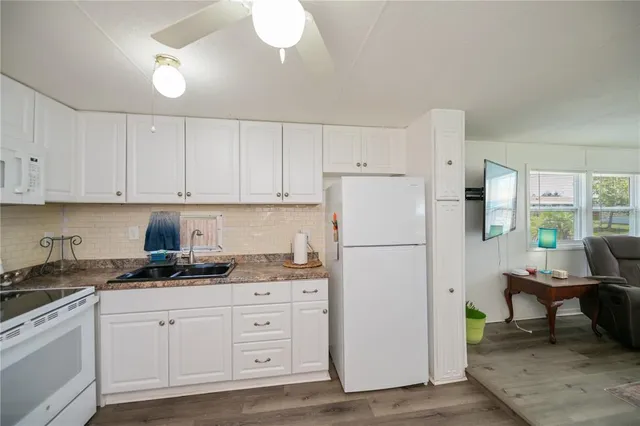 a kitchen with stainless steel appliances granite countertop a stove a sink and a refrigerator with wooden floors