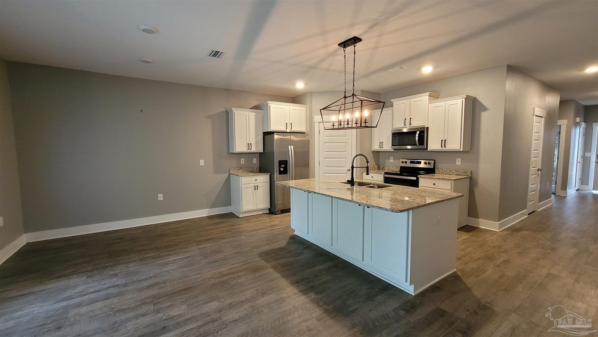 5748 Conley Court Pace, FL 32571 - Photo 7 of 22 a kitchen with kitchen island white cabinets and stainless steel appliances