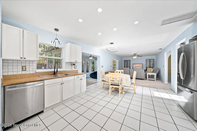 a large white kitchen with a large window and stainless steel appliances