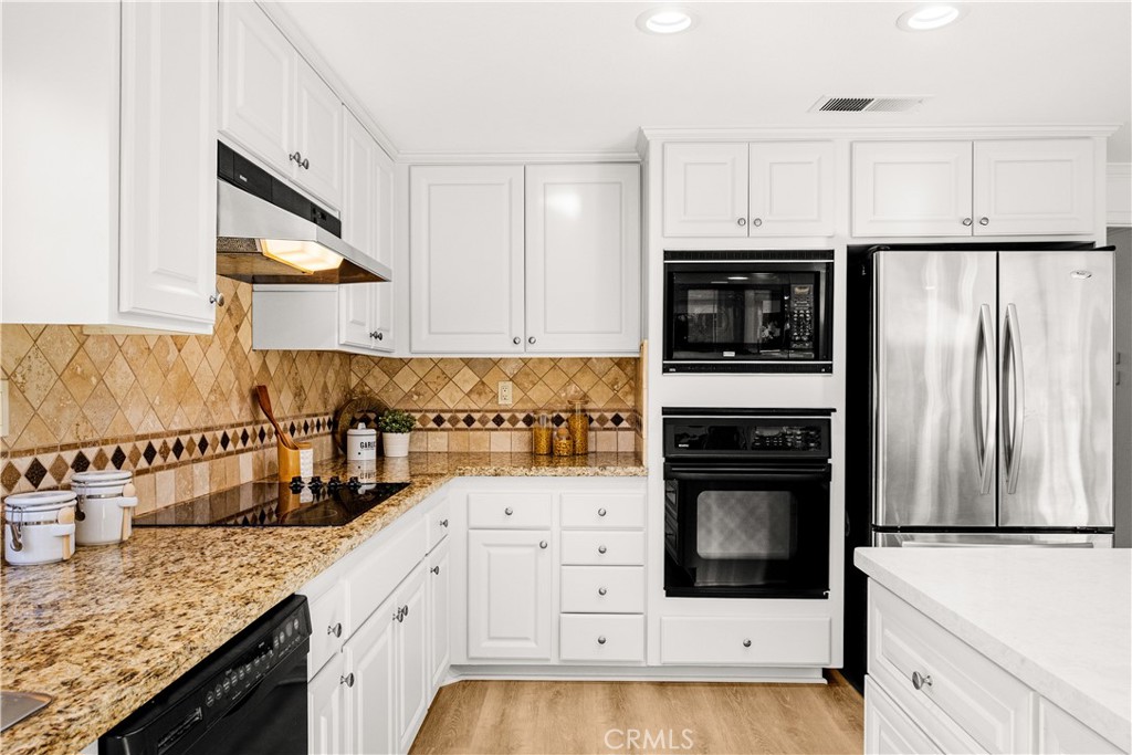 19 Alameda Irvine, CA 92620 - Photo 11 of 59 a kitchen with granite countertop white cabinets and stainless steel appliances