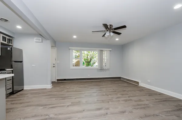 an empty room with window ceiling fan and hardwood floor