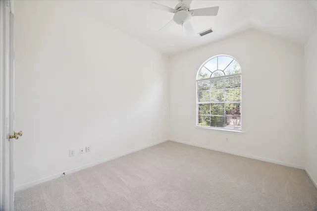 an empty room with a window and a ceiling fan