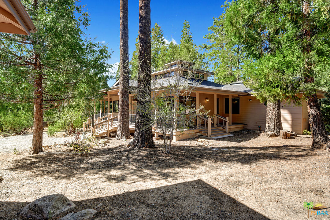 25445 Fern Valley Road Idyllwild, CA 92549 - Photo 5 of 52 a view of a white house with a large tree next to a yard