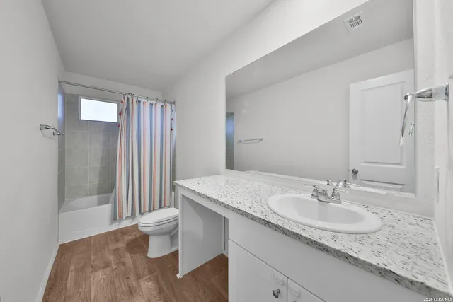 a bathroom with a granite countertop sink a toilet and shower