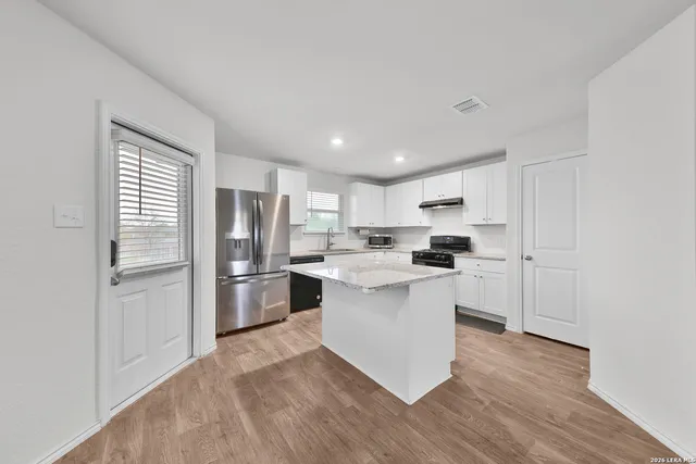 a kitchen with a refrigerator and white cabinets