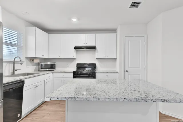 a kitchen with stainless steel appliances granite countertop a sink stove and cabinets