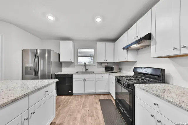 a kitchen with stainless steel appliances granite countertop a sink stove and refrigerator