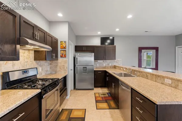 a large kitchen with stainless steel appliances granite countertop a sink stove and refrigerator