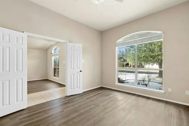 an empty room with wooden floor and windows