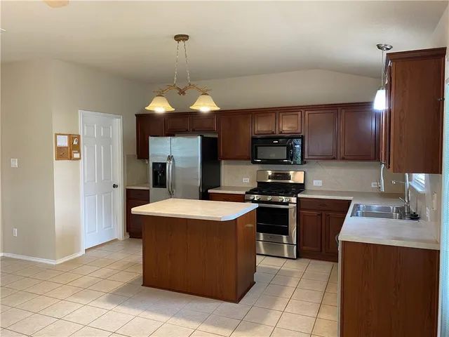 a kitchen with stainless steel appliances granite countertop a stove refrigerator sink and microwave