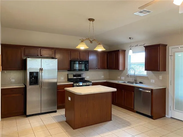 a kitchen with stainless steel appliances granite countertop a sink a stove a refrigerator and cabinets