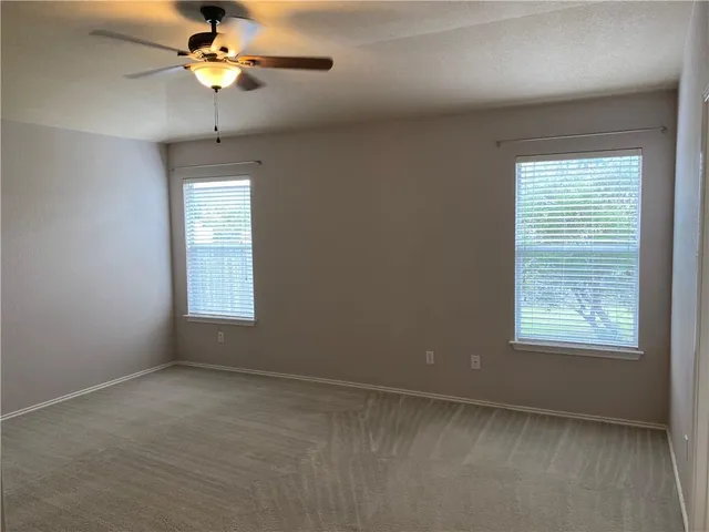 an empty room with a window and a fan