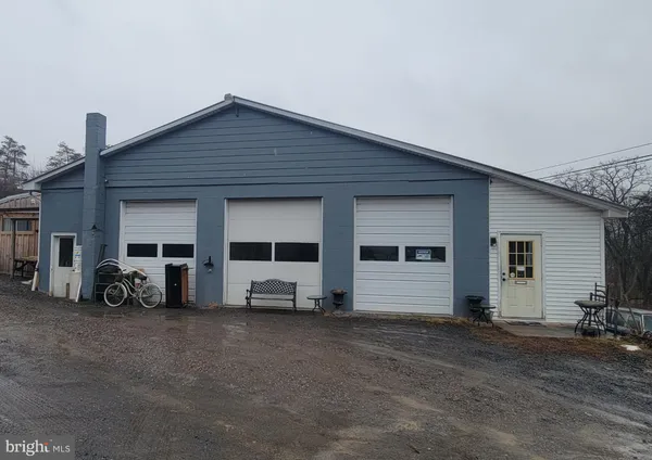 a view of a house with a barbeque and large trees