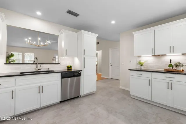 a kitchen with granite countertop white cabinets and stainless steel appliances