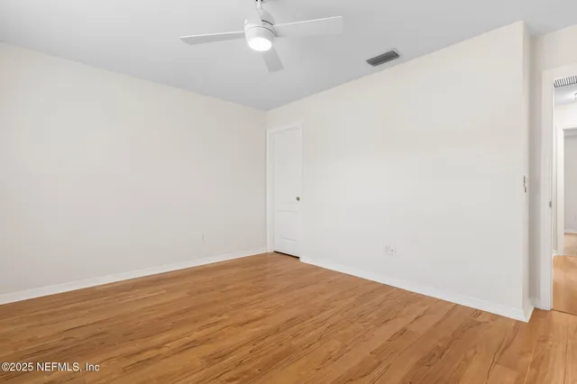 an empty room with wooden floor and fan