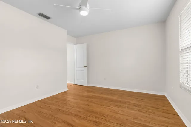 an empty room with wooden floor and windows