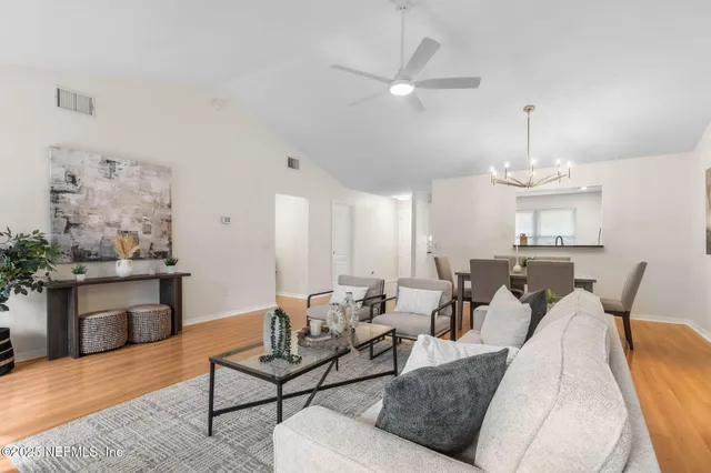 a living room with furniture kitchen view and a chandelier