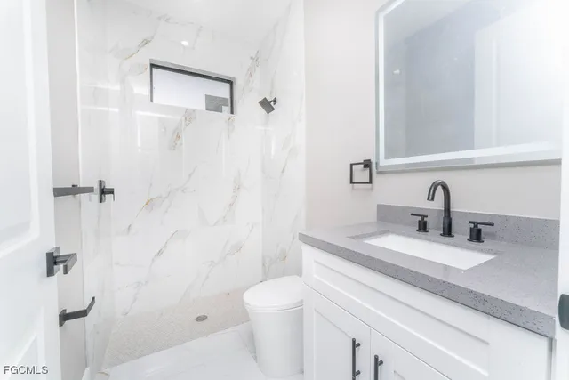 a bathroom with a granite countertop sink a toilet and shower