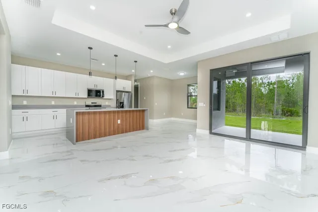 a view of an empty room with kitchen view and a floor to ceiling window