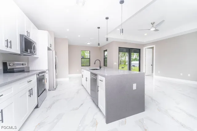 a large kitchen with stainless steel appliances kitchen island granite countertop a refrigerator a stove a sink dishwasher and white cabinets with wooden floor