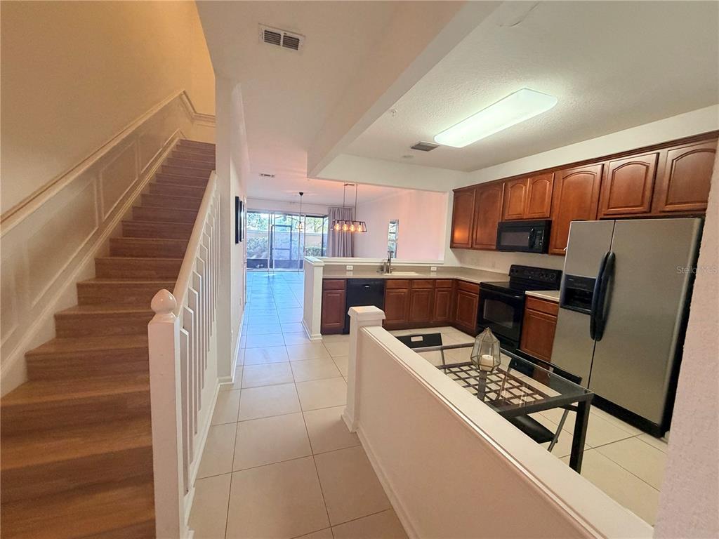 2837 Villafuerte Point, Unit 105 Orlando, FL 32835 - Photo 5 of 23 a kitchen with granite countertop a refrigerator and a stove top oven