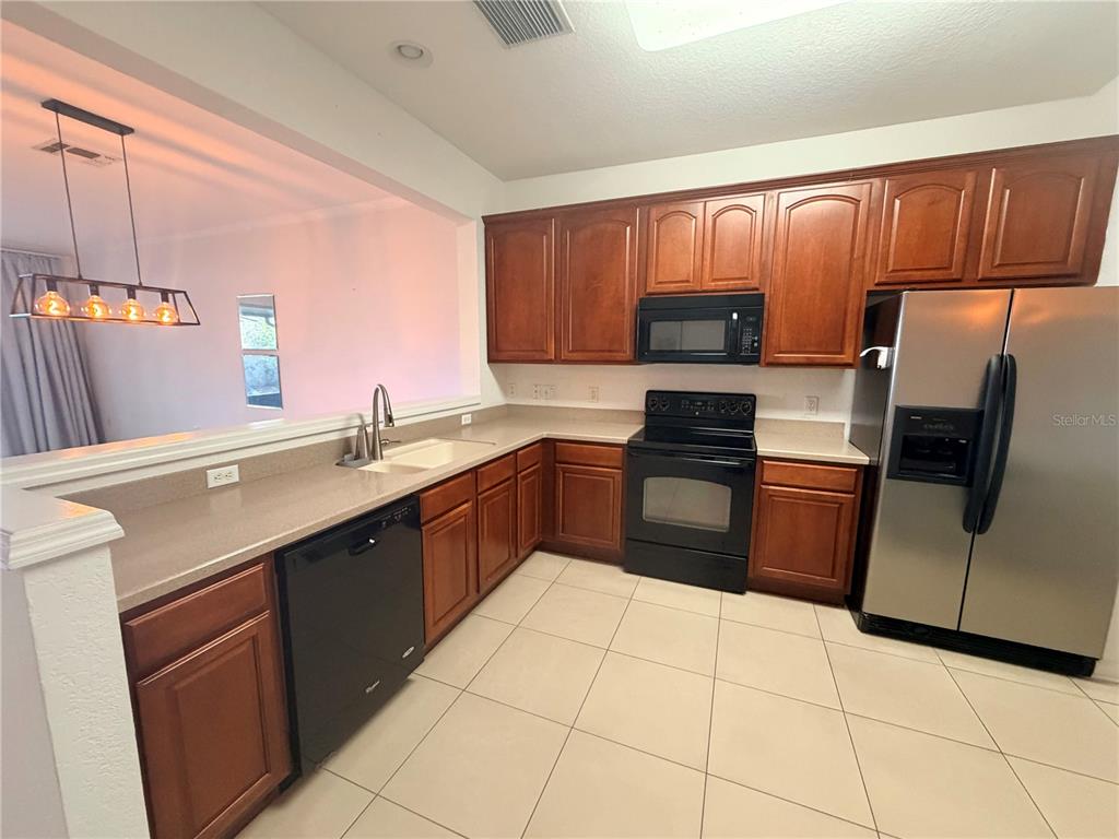 2837 Villafuerte Point, Unit 105 Orlando, FL 32835 - Photo 6 of 23 a kitchen with stainless steel appliances granite countertop a sink stove and refrigerator